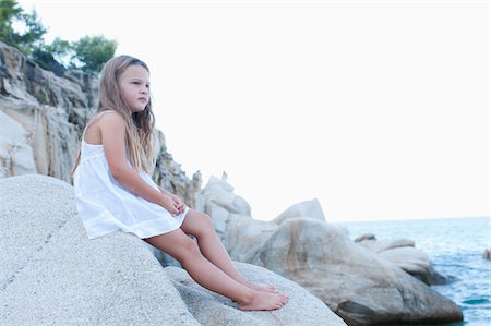 Girl Sitting on Boulders at Beach Foto de stock - Con derechos protegidos, Código: 700-03739277