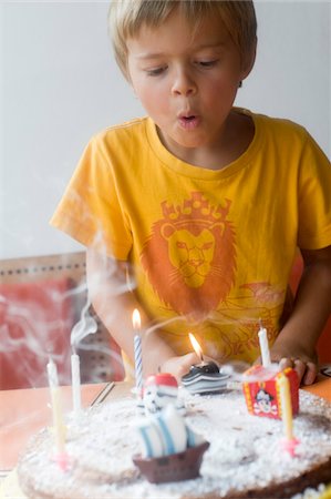 Boy Blowing out Candles on Birthday Cake Foto de stock - Con derechos protegidos, Código: 700-03777788