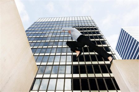 Businesswoman Jumping Gap in front of Office Building Foto de stock - Con derechos protegidos, Código: 700-03778616