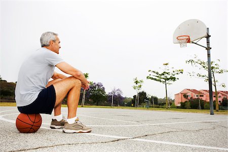 panier de basket-ball - Homme assis sur le basket-ball sur le terrain de basket Photographie de stock - Rights-Managed, Code: 700-03784263