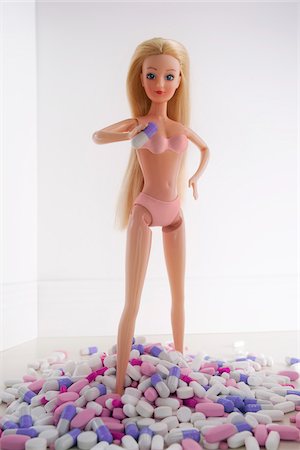 feminine objects - Blond Doll Standing on Pile of Diet Pills Stock Photo - Rights-Managed, Code: 700-03815222