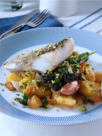 A baked fillet of pollock on a bed of crispy crushed Charlotte potatoes with purple sprouting broccoli sage and garlic and gremolata sauce Photographie de stock - Rights-Managed, Code: 824-07585823