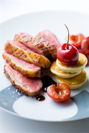 Sliced duck Magret with cherry sauce and mini blinis Foto de stock - Con derechos protegidos, Código: 825-05815623