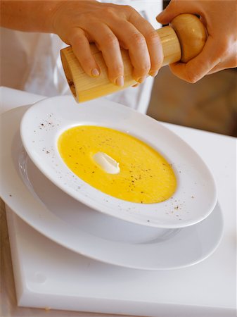 simsearch:825-06047515,k - Putting pepper on to the cream of carrot soup Foto de stock - Direito Controlado, Número: 825-06047516