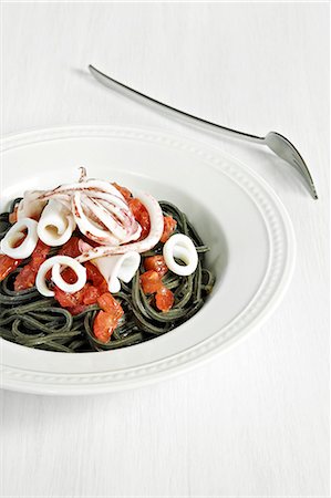 Squid ink pasta with squid and tomatoes Foto de stock - Con derechos protegidos, Código: 825-07076514