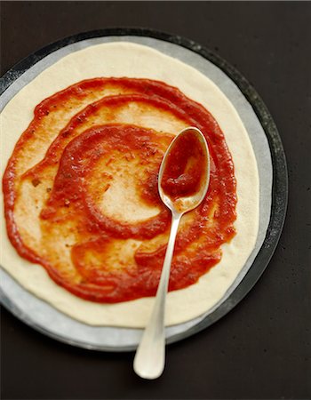 salsa de tomate - Spreading tomato paste on the uncooked pizza Foto de stock - Con derechos protegidos, Código: 825-07652945