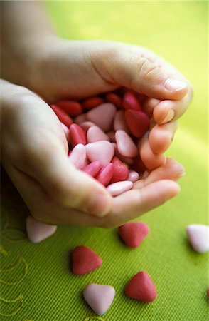 Child's hands holding heart-shaped sweets Fotografie stock - Rights-Managed, Codice: 825-03627610