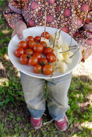 finger food people - Child holding a plate of cherry tomatoes and diced gruyere for aperitifs Stock Photo - Rights-Managed, Code: 825-03628424