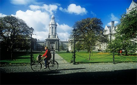 Woman riding a bicycle in front of a building, Trinity College, Dublin, Republic Of Ireland Foto de stock - Con derechos protegidos, Código: 832-03358679