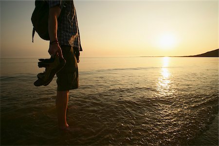 Homme patauger dans l'eau sur la plage au coucher du soleil Photographie de stock - Rights-Managed, Code: 832-03724971