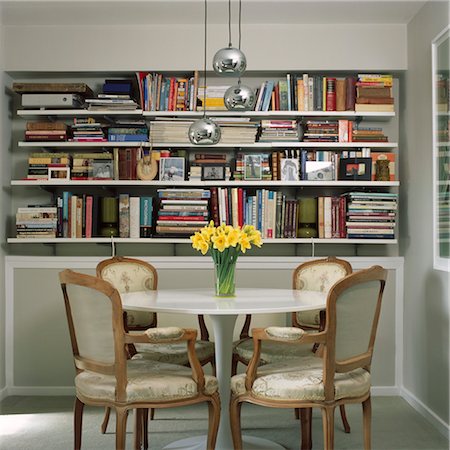 daffodil - Circular pedestal base dining table with chairs in room with extensive book collection, UK. Stock Photo - Rights-Managed, Code: 845-05837848