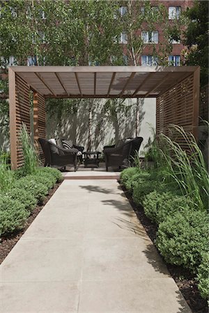 seats back - Slatted cedar pavilion on the right side of the lawn on the upper level of the garden. Silver birches along the boundary wall to the rear. sawn sandstone path lined with hebe and grasses. Designed by Modular in conjunction with the architects commissioned by the owners to renovate the house. Architects: Modular Stock Photo - Rights-Managed, Code: 845-05838300