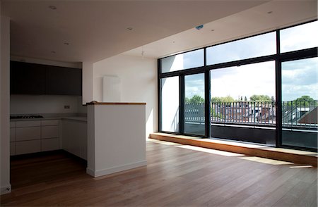 empty room with wooden floor - Large empty kitchen and living area, penthouse in Modern Apartments, Hampton Wick. Doors partially open. Architects: Abimara Construction Stock Photo - Rights-Managed, Code: 845-05838414