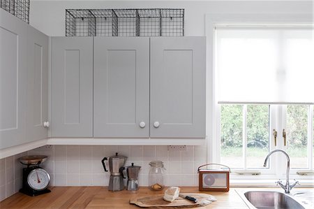 european interior houses - Grey painted cupboards and workbench at kitchen window of beach house, Sandways, Camber Sands, UK. Stock Photo - Rights-Managed, Code: 845-07584916