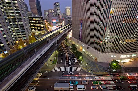 simsearch:855-06314302,k - A wide-angle view and a slow shutter speed capture a Shinkansen bullet train streaking past the Yurakucho Mullion Building, crossing Daimyyokoji Avenue and Harumi Dori Avenue, and cutting right through the middle of the Yurakucho District at twilight in central Tokyo, Japan. Stock Photo - Rights-Managed, Code: 845-08939713