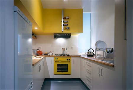 simsearch:845-05838842,k - Glasgow Loft, Scotland. Compact kitchen with yellow cooker, yellow wall and vertical wine rack. Architects: Gareth Hoskins Architects. Designed by Designed by David Churchill, Phillipa Vafadari Foto de stock - Direito Controlado, Número: 845-03721510