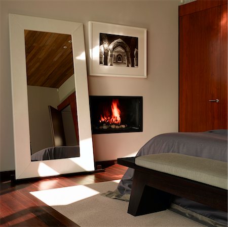Ad Astra. Chambre à coucher avec un grand miroir de chaudières au sol et cheminée allumée intégrée. Architectes : Munkenbeck et Marshall Photographie de stock - Rights-Managed, Code: 845-03777236