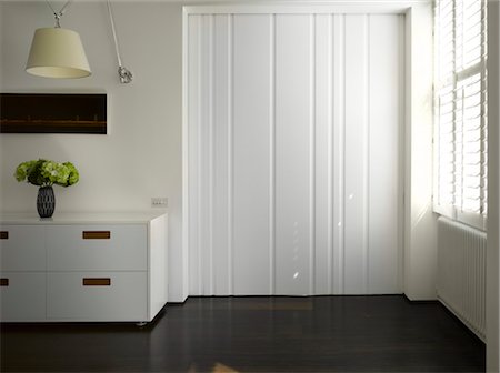 simsearch:845-05837886,k - Slide Apartment, Bayswater. White uncluttered living room with dark timber floor, low storage chest and sah window with narrow venetian blinds. Architects: Openstudio Architects- Jennifer Benningfield - Foto de stock - Con derechos protegidos, Código: 845-03777488