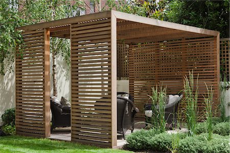 simsearch:845-05838459,k - Slatted cedar pavilion on the right side of the lawn on the upper level of the garden. Silver birches along the boundary wall. Hebe and grasses on the right. Architects: Modular Stock Photo - Rights-Managed, Code: 845-03777659