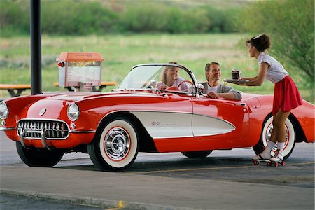 1990s COUPLE IN 1950s CORVETTE WAITRESS ON ROLLER SKATES AT CAR HOP GRANBY COLORADO USA Foto de stock - Con derechos protegidos, Código: 846-05645742