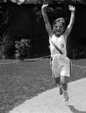 simsearch:846-05647682,k - 1930s BOY IN TRACK UNIFORM WITH ARMS IN AIR BREAKING TAPE AT FINISH LINE Foto de stock - Con derechos protegidos, Código: 846-05645949