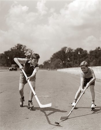 simsearch:846-05645990,k - 1930s - 1940s 2 BOYS WITH STICKS AND PUCK WEARING ROLLER SKATES PLAYING STREET HOCKEY Foto de stock - Direito Controlado, Número: 846-05645990