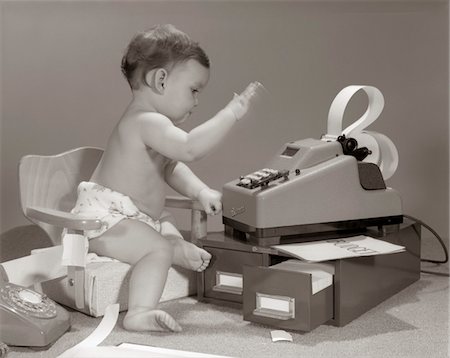 1960s BABY SEATED IN SMALL CHAIR HITTING KEYS ON OFFICE ADDING MACHINE ON TOP OF SMALL FILE DRAWERS Foto de stock - Con derechos protegidos, Código: 846-05646016