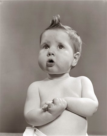 facial expression - 1950s WORRIED BABY LOOKING UP UNCERTAIN WITH CLASPED HANDS STUDIO Foto de stock - Con derechos protegidos, Código: 846-05646082