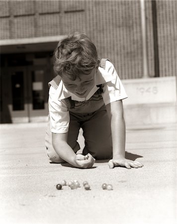 simsearch:846-05647435,k - 1950ER JAHRE LÄCHELND BOY BEREIT ZU SCHIEßEN, KNIEND AUF SCHOOL YARD BODEN SPIEL MIT MURMELN SPIELEN Stockbilder - Lizenzpflichtiges, Bildnummer: 846-05646095