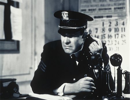 poliziotto (uomo) - 1930s - 1940s CONCERNED DETERMINED MAN POLICE SERGEANT IN STATION HOUSE TALKING ON CANDLE STICK TELEPHONE Fotografie stock - Rights-Managed, Codice: 846-05646168