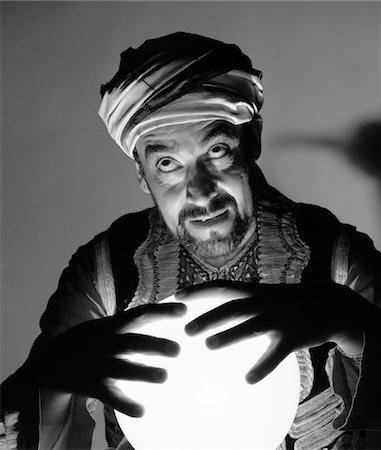 1970s SCARY FORTUNE TELLER MAN WITH HANDS ON LIGHTED CRYSTAL BALL WEARING TURBAN Fotografie stock - Rights-Managed, Codice: 846-05646182