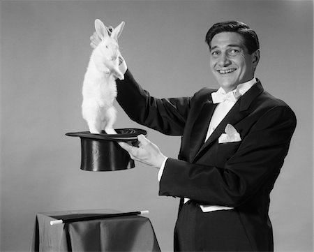 1960s MAN PORTRAIT SMILING MAGICIAN PULLING WHITE RABBIT OUT OF TOP HAT Stock Photo - Rights-Managed, Code: 846-05646236