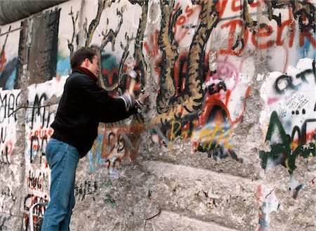 1980s TEENAGE BOY CHIPPING AWAY AT THE GRAFFITI SPRAY PAINTED BERLIN WALL WITH HAMMER AND CHISEL NOVEMBER 1989 Stock Photo - Rights-Managed, Code: 846-05646248