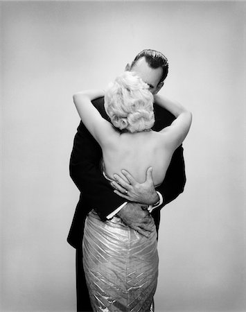 simsearch:846-09181904,k - 1950s - 1960s KISSING COUPLE BLOND WOMAN BACKLESS SATIN EVENING DRESS MAN EMBRACING FROM BEHIND Foto de stock - Con derechos protegidos, Código: 846-05646306