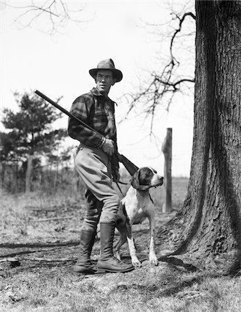 simsearch:846-03163283,k - ANNÉES 1930 L'HOMME CHASSEUR PORTANT CHAPEAU PLAID FLANNEL SHIRT JODHPURS ET BOTTES DEBOUT TENANT LE FUSIL DE CHASSE AVEC CHIEN POINTEUR Photographie de stock - Rights-Managed, Code: 846-05646382