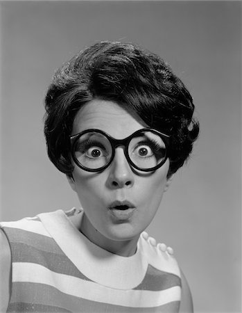 1960s PORTRAIT BRUNETTE WEARING DARK THICK ROUND EYEGLASSES WITH EYES WIDE OPEN Foto de stock - Con derechos protegidos, Código: 846-05646426