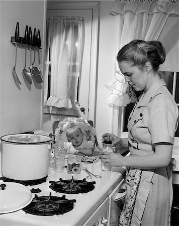 simsearch:846-02793227,k - 1950s BABY IN HIGHCHAIR WATCHING MOTHER IN KITCHEN AT STOVE PREPARING BABY'S MILK BOTTLE Stock Photo - Rights-Managed, Code: 846-05646452