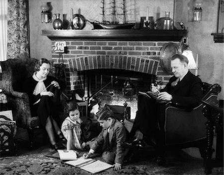 simsearch:846-02793852,k - 1930s FAMILY OF FOUR SITTING IN FRONT FIREPLACE MOTHER KNITTING FATHER READING SMOKING PIPE KIDS DOING HOMEWORK Stock Photo - Rights-Managed, Code: 846-05646502