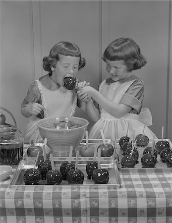 simsearch:846-02797122,k - 1950s TWO TWIN GIRLS EATING MAKING CANDY APPLES IN KITCHEN Stock Photo - Rights-Managed, Code: 846-05646521
