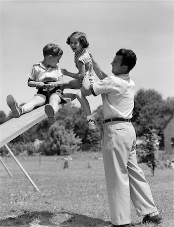 simsearch:846-05646094,k - 1950s FATHER LIFTING SON AND DAUGHTER ONTO A PLAYGROUND SEESAW OUTDOOR Foto de stock - Con derechos protegidos, Código: 846-05646543