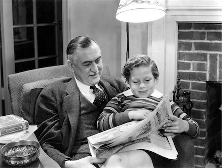 simsearch:846-02793841,k - 1930s - 1940s FATHER SITTING WITH SON ON LAP READING SUNDAY NEWSPAPER COMICS TOGETHER IN LIVING ROOM Stock Photo - Rights-Managed, Code: 846-05646578