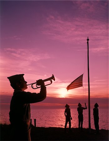 simsearch:846-05646191,k - 1960s BOY SCOUT BLOWING BUGLE AS OTHERS RAISE AMERICAN FLAG AT CAMP SUNSET CEREMONY Stock Photo - Rights-Managed, Code: 846-05646704