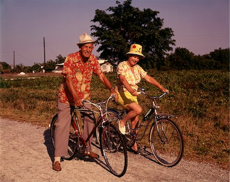 1970s SENIOR ELDERLY RETIRED COUPLE RIDING BIKES WEARING STRAW HATS HAWAIIAN PRINT SHIRTS Stock Photo - Rights-Managed, Code: 846-05646711