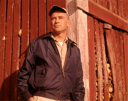 1960s MAN FARMER SERIOUS PORTRAIT LEANING AGAINST CORN CRIB WEARING CAP AND JACKET Foto de stock - Con derechos protegidos, Código: 846-05646916