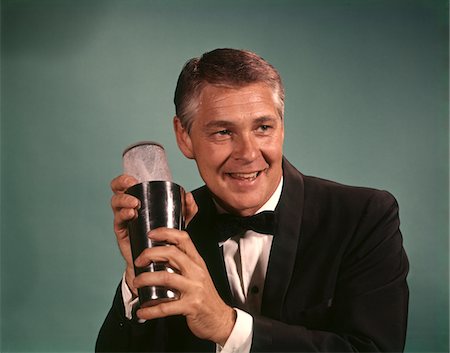 1960s - 1970s BARTENDER SMILING MAN IN BLACK TUXEDO MIXING COCKTAIL IN SHAKER Foto de stock - Con derechos protegidos, Código: 846-05646928