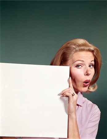 simsearch:846-05648209,k - 1960s PORTRAIT OF SURPRISED WOMAN PEEKING AROUND SIGN BOARD Fotografie stock - Rights-Managed, Codice: 846-05646957