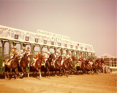 fantino (uomo e donna) - 1960s ELEVEN RACE HORSES AND JOCKEYS COMING OUT OF STARTING GATE Fotografie stock - Rights-Managed, Codice: 846-05647011