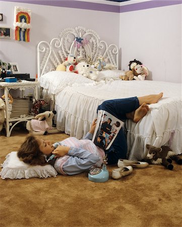 década de 1980 - 1980s TEENAGE GIRL LYING ON BEDROOM FLOOR READING MAGAZINE TALKING ON TELEPHONE Foto de stock - Direito Controlado, Número: 846-05647073