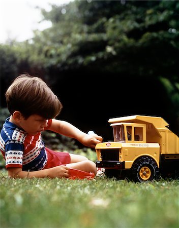 ANNÉES 1970 GARÇON EN HERBE JOUANT AVEC LE CAMION À BENNE TONKA JOUET JAUNE Photographie de stock - Rights-Managed, Code: 846-05647147