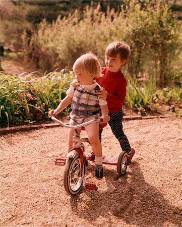 simsearch:846-05647208,k - 1960s - 1970s YOUNG BOY AND GIRL PLAYING TOGETHER RIDING TRICYCLE Stock Photo - Rights-Managed, Code: 846-05647143